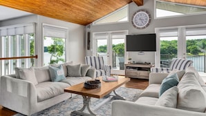 A spacious living room with a wooden ceiling, large windows, a flat-screen TV, and a cozy seating area with a coffee table. - Expansive Retreat with Heated Pool & Gorgeous Views (Cullman)
