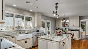 A spacious kitchen with a large island, white cabinetry, and a stone backsplash. - Expansive Retreat with Heated Pool & Gorgeous Views (Cullman)