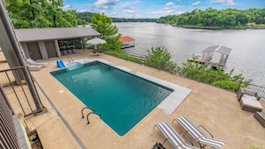 A rectangular swimming pool with a deck, lounge chairs, and a covered seating area. - Expansive Retreat with Heated Pool & Gorgeous Views (Cullman)