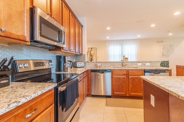 A modern kitchen with wooden cabinets, stainless steel appliances, granite countertops, and a dishwasher.