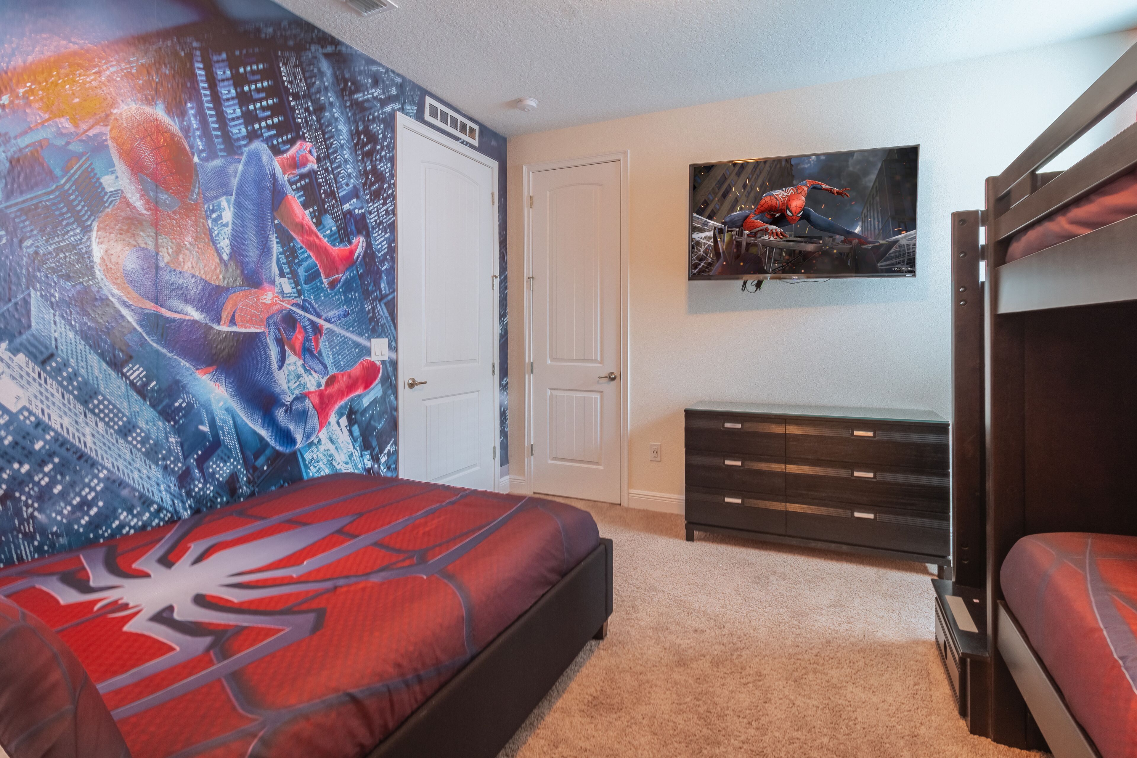A bedroom with a bed, a dresser, a TV, and a door.