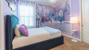 Une chambre à coucher comprenant un lit, une table de chevet, une lampe et une fresque murale représentant une forêt enneigée.
