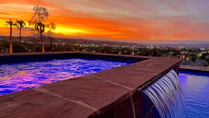 Una piscina con cascata e vista sul tramonto.