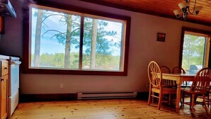 A room with a large window, wooden floor, and a dining table with chairs. - Lakefront Muskoka Good View cottage (Gravenhurst)