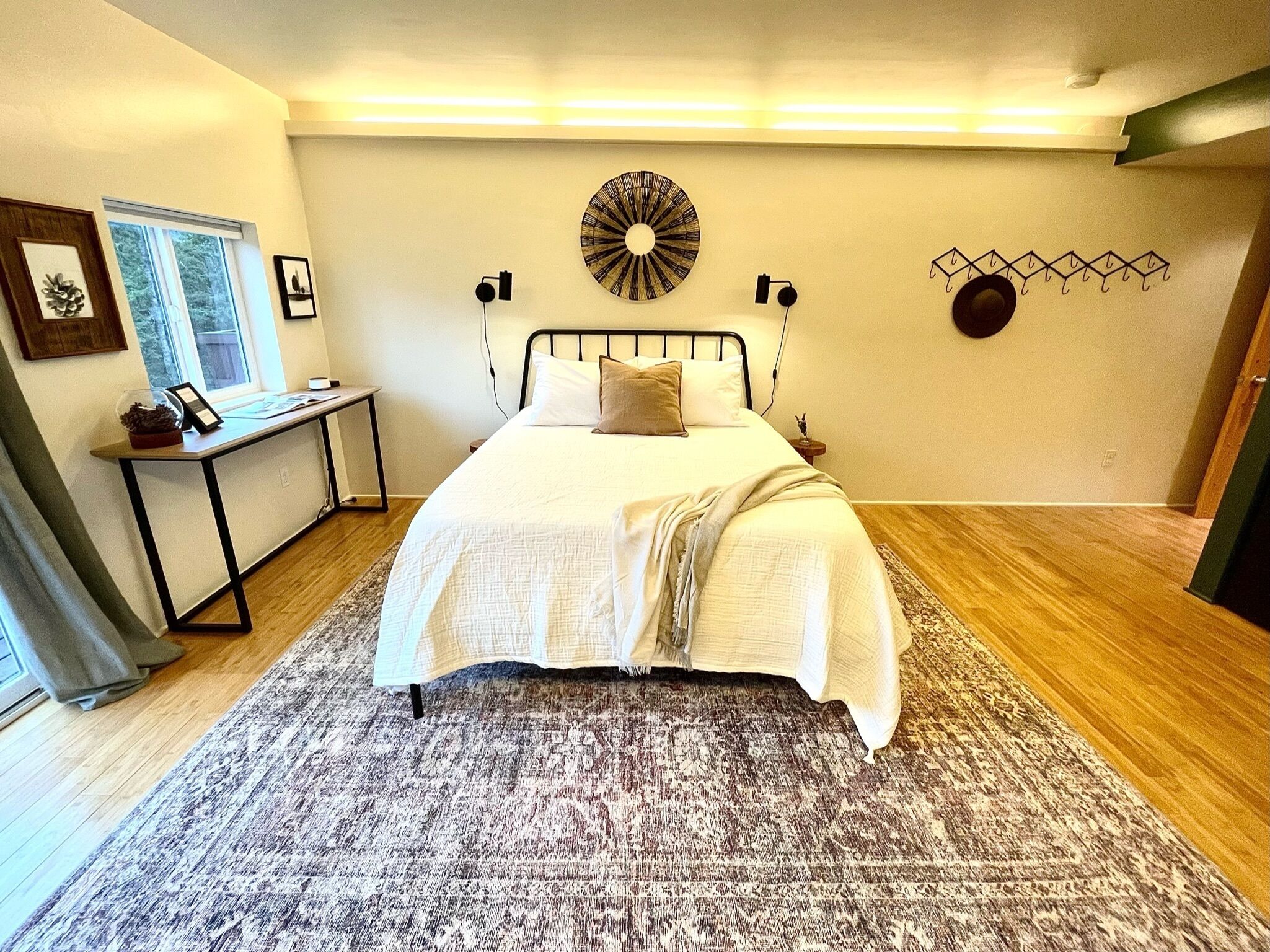 Un dormitorio con cama, mesita de noche, decoración en la pared y una ventana.