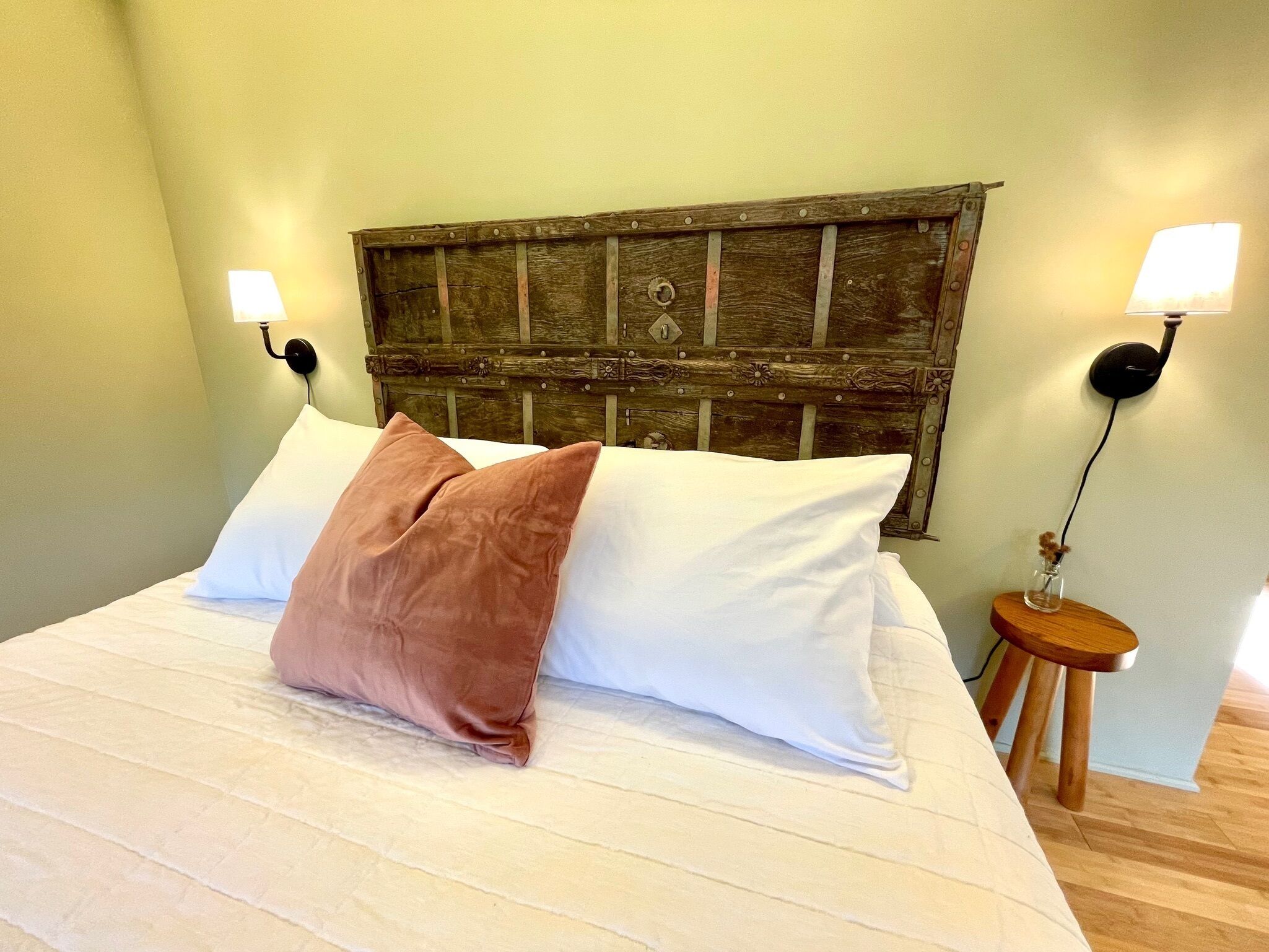 A bed with white and brown pillows, a wooden headboard, and two wall-mounted lamps.