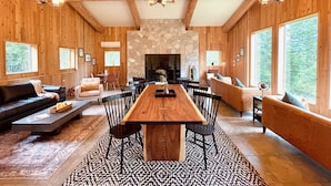 Un amplio salón con una mesa de comedor de madera, sillas negras y una chimenea de piedra.