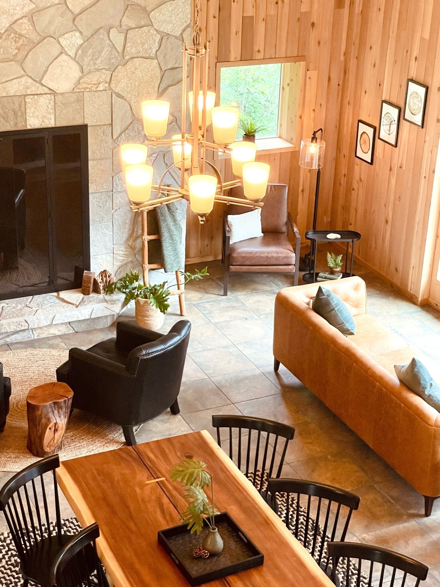 Una sala de estar acogedora con chimenea de piedra, muebles de madera y una lámpara moderna.