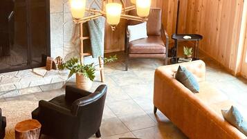 Una sala de estar acogedora con chimenea de piedra, muebles de madera y una lámpara moderna.