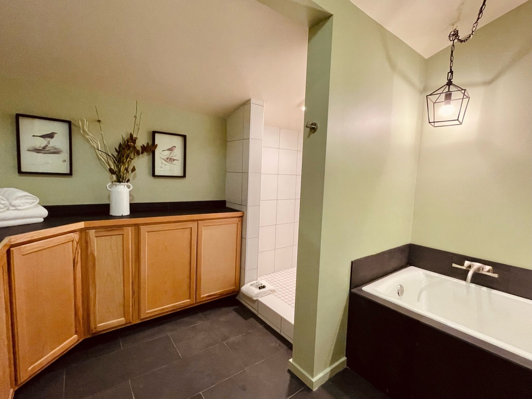 A modern bathroom with a freestanding bathtub, wooden cabinetry, and a tiled shower area.