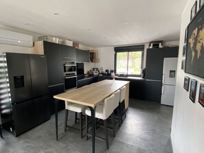Una cocina moderna con electrodomésticos negros, una mesa de comedor de madera y un ventanal grande.