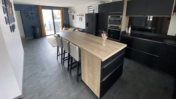 A modern kitchen with a wooden island, black cabinets, and stainless steel appliances. - Maison Individuelle Entre Océan et Forêt (Anglet)