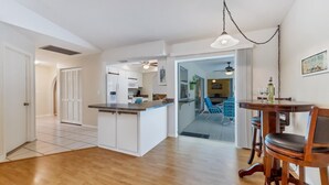 A modern kitchen with white cabinets, a wooden countertop, and a dining area with a wooden table and chairs.