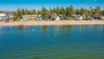 A waterfront property with multiple buildings, a sandy beach, and a calm body of water.