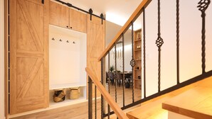 A wooden staircase with a black railing, leading to a room with a white wall and a wooden door. - Villa Velebita (Zadar)