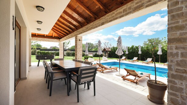 An outdoor patio with a pool, wooden deck, and lounge chairs. - Villa Velebita (Zadar)