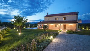 A two-story house with a paved driveway, a well-maintained lawn, and a satellite dish on the roof. - Villa Velebita (Zadar)