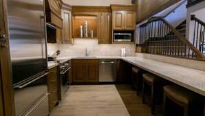 A modern kitchen with wooden cabinets, stainless steel appliances, and a marble countertop.