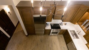 A modern kitchen with wooden cabinets, stainless steel appliances, and pendant lighting.