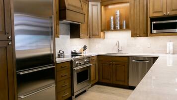 A modern kitchen with stainless steel appliances, wooden cabinets, and a marble countertop.