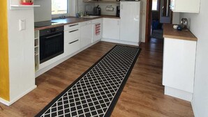 Une cuisine moderne avec des meubles blancs, un tapis au motif noir et blanc et une fenêtre laissant entrer la lumière naturelle.