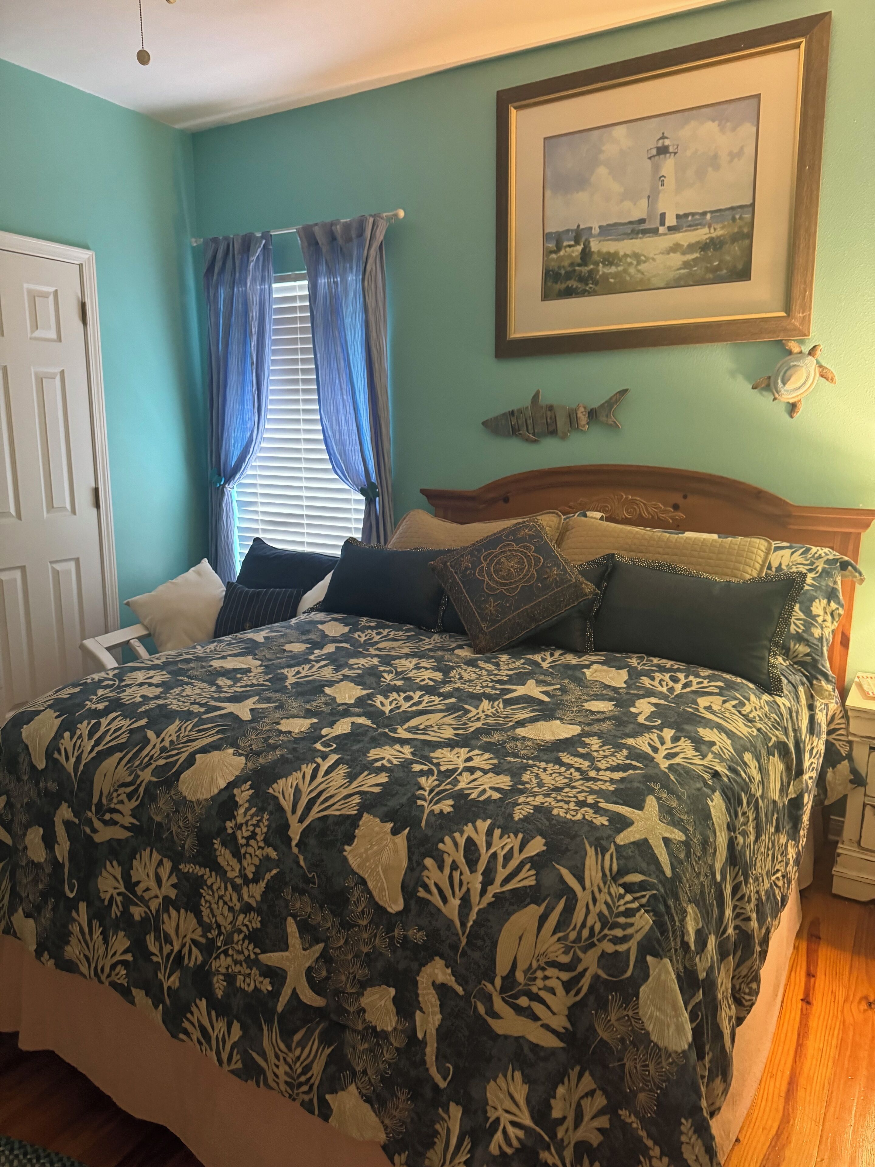 Une chambre à coucher avec un lit, des rideaux, un tableau encadré et une décoration représentant une tortue.