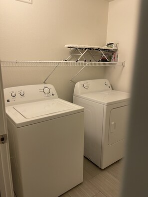 Convenient laundry facilities with two front-loading washing machines and storage space.