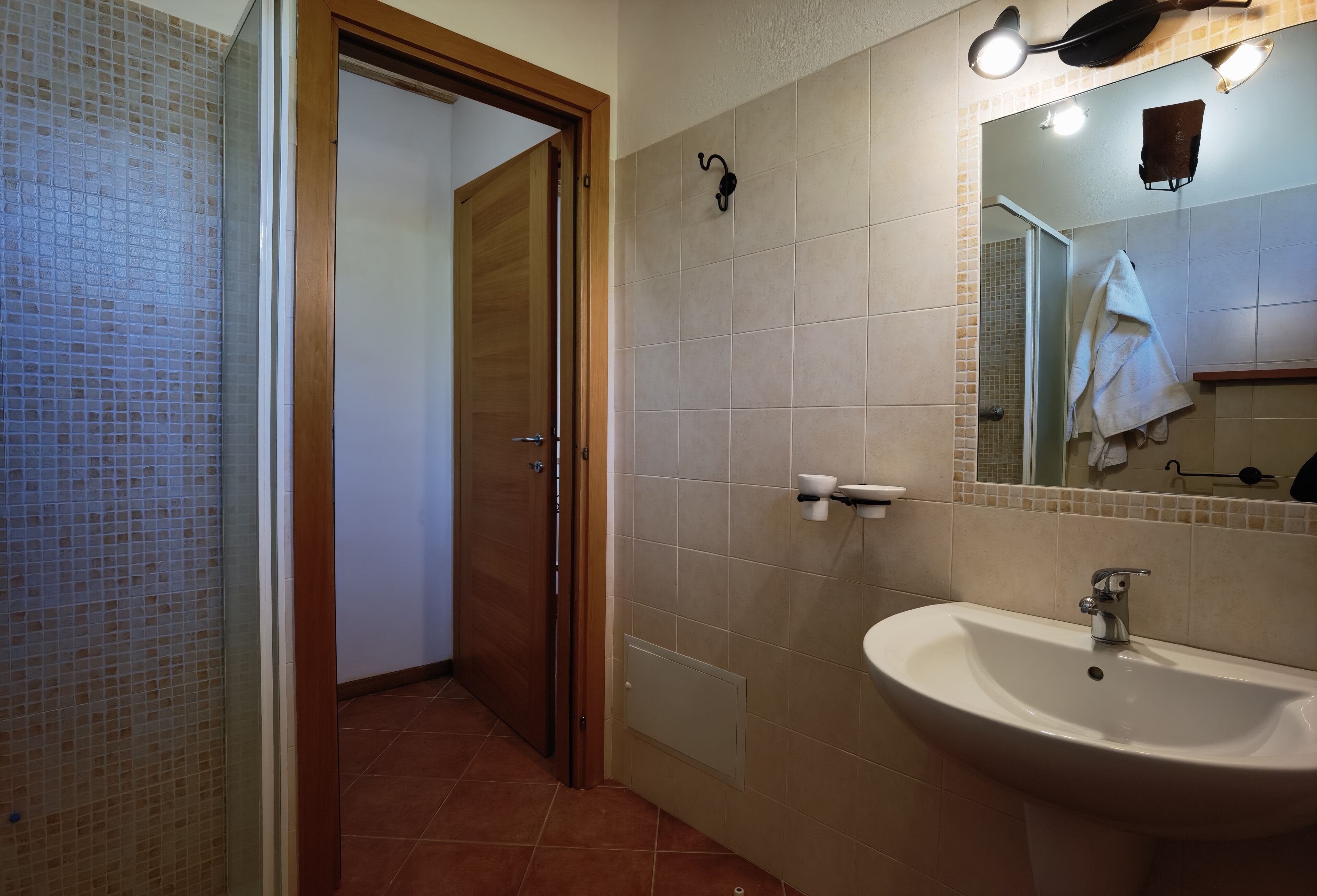 Un baño con lavamanos, espejo y paredes con azulejos.
