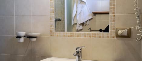 Un baño con lavamanos blanco, espejo y ducha.