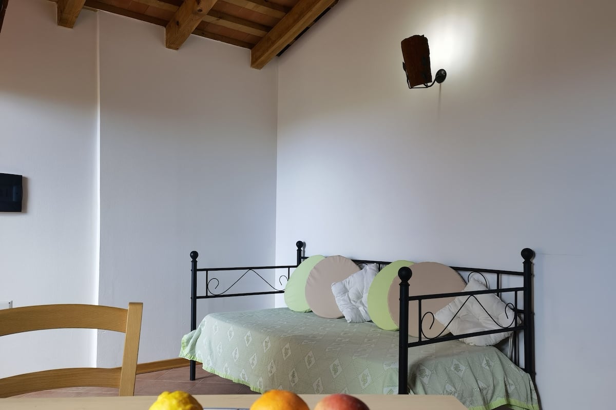 Un dormitorio con una cama, una silla y una mesa con fruta.