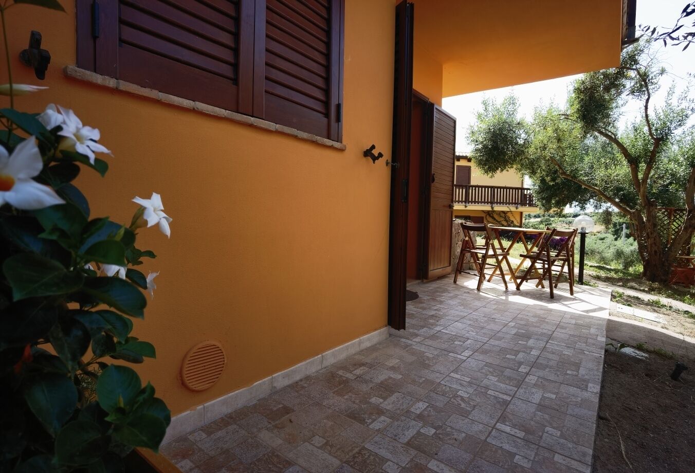 A patio area with a table and chairs, a wooden door, and a window with shutters.