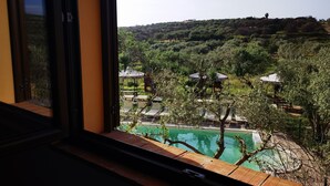 A view of a swimming pool surrounded by trees and gazebos, visible through a window. - la corte degli ulivi (Tresnuraghes)