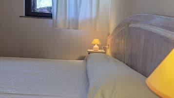 Una camera da letto con un letto, un comodino con una lampada e una finestra con tende.