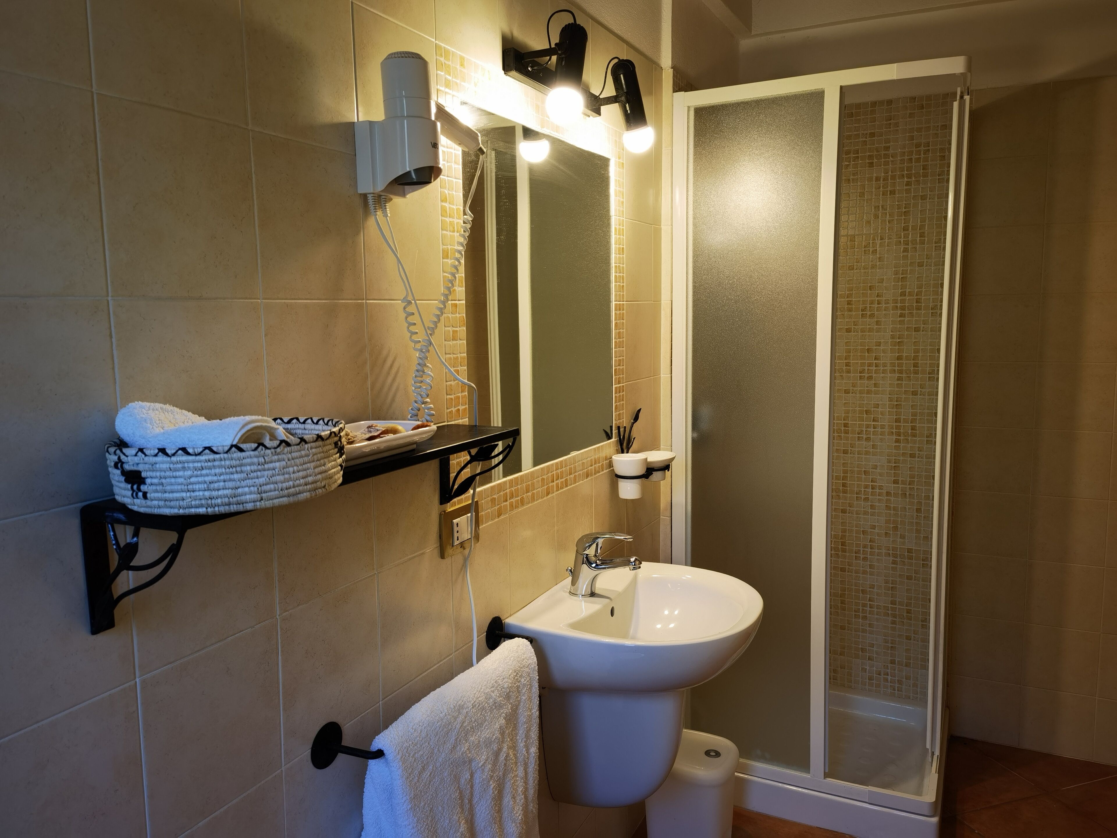 Un baño con lavabo, espejo, toallero y zona de ducha.