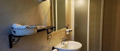 Une salle de bain équipée d’un lavabo, d’un miroir, d’un porte-serviettes et d’un espace douche.