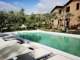 Una piscina al aire libre de temporada, sillones reclinables de piscina