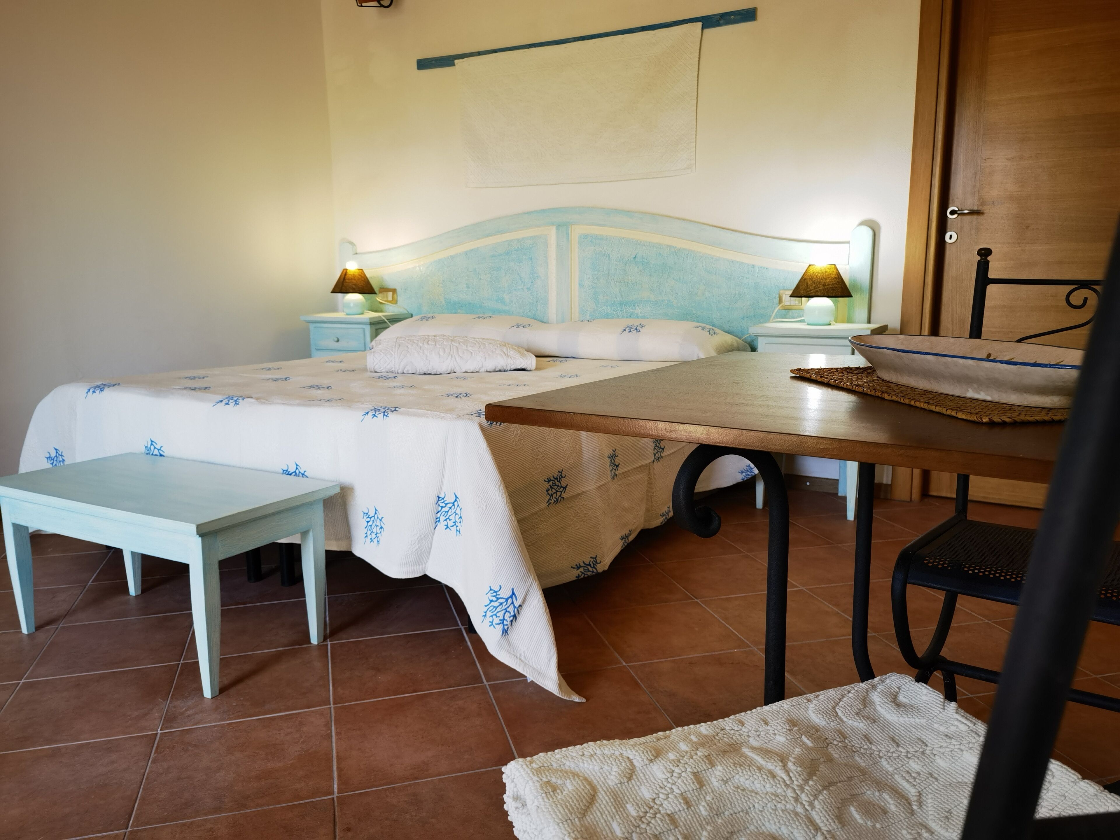 Une chambre à coucher comprenant un lit, des tables de chevet, un banc et une table avec un bol.