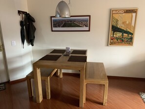 A dining area with a wooden table and bench, a framed cityscape photo, and a poster on the wall.
