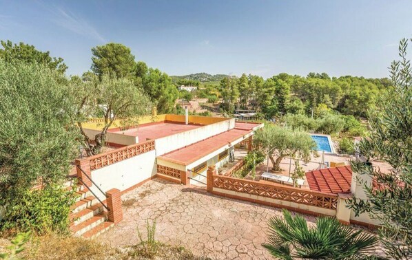 Enjoy a rooftop retreat with a pool and lounge chair amidst lush greenery and a hilly landscape.