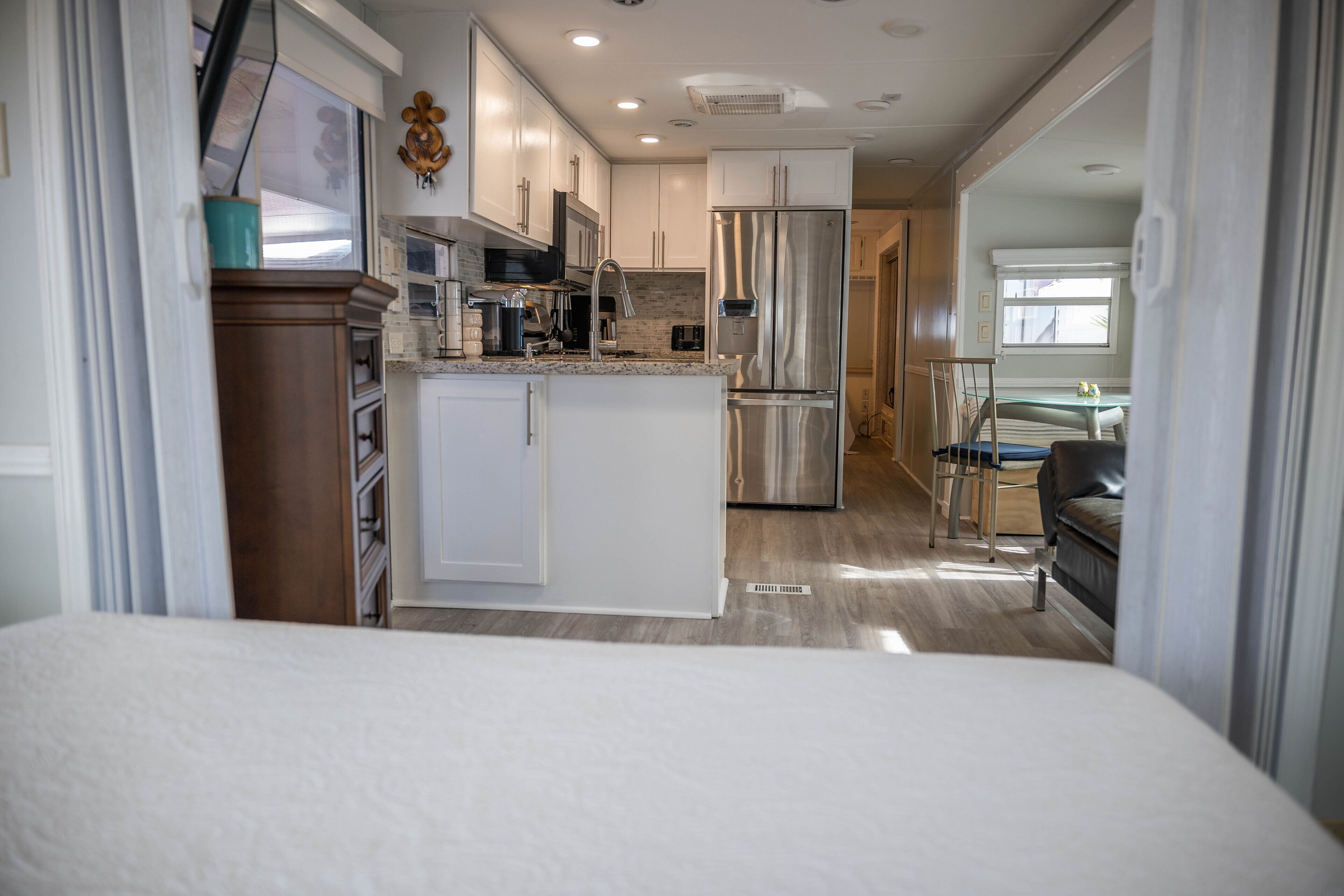 Cocina compacta con muebles blancos, un refrigerador de acero inoxidable y una pequeña isla.