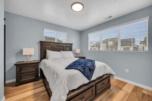 A bedroom with a bed, nightstands, and a window with blinds.