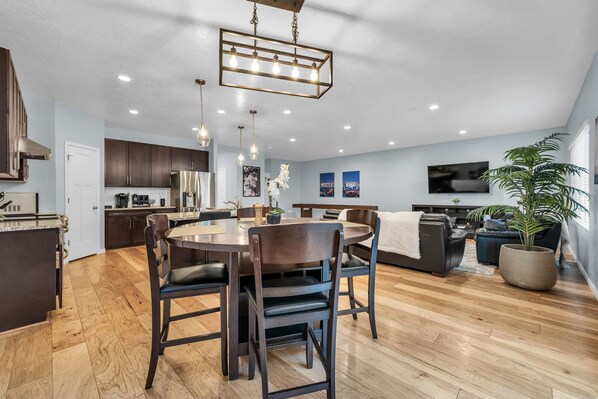 A spacious living area with a dining table, chairs, a sofa, and a TV.