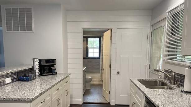 A kitchen with granite countertops, white cabinets, a built-in dishwasher, and a coffee maker. - Home Near Main Street-Covered Patio-Hot Tub! (Saint Charles)