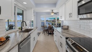 A modern kitchen with white cabinets, a large island, and a view of the water.