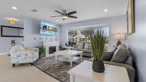 A living room with a fireplace, a ceiling fan, a television, and a sofa.