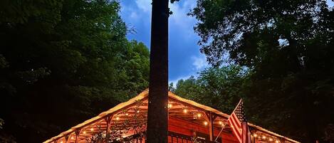 Een houten hut met een veranda, omringd door bomen, en een Amerikaanse vlag.