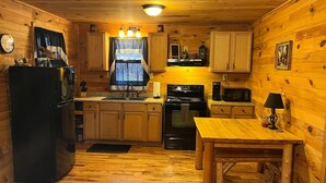 Una cocina compacta con armarios de madera, un refrigerador, estufa, microondas y una mesa de comedor.