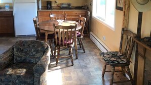 A kitchen with wooden cabinets, a white refrigerator, a dining table with chairs, and a ceiling fan. - A hunter's/Getaway Paradise (Council)