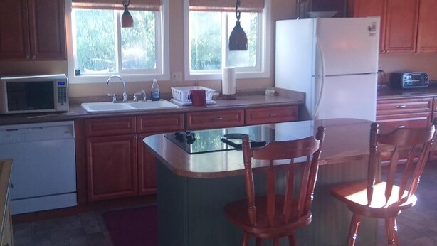 A kitchen with wooden cabinets, a refrigerator, a microwave, and a sink. - A hunter's/Getaway Paradise (Council)