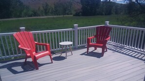 A wooden deck with two red Adirondack chairs and a small round table. - A hunter's/Getaway Paradise (Council)